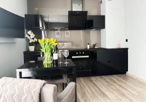 トルンにあるApartament Chełmionkaのキッチン(黒いキャビネット、ワイングラス付きのテーブル付)