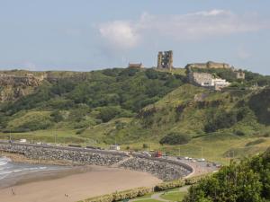 a view of a beach with a castle on a hill at The Newborough - 1 Bedroom Apartment in Scarborough