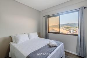 a bedroom with a bed and a large window at CTDs - Apartamentos no Centro de Penha! in Penha