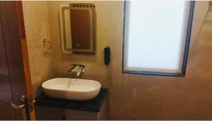 baño con lavabo blanco y ventana en Mussoorie Nature Stay, en Mussoorie