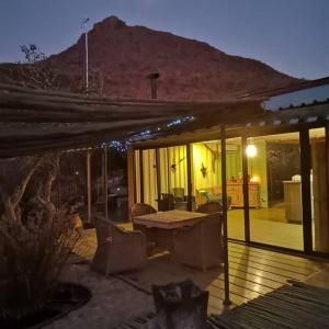 a house with a wooden deck with a table and chairs at Guestfarm Camp Oubokberg in Omaruru