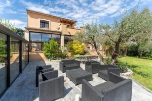 a patio with chairs and tables in front of a house at Villa spacieuse à Vézénobres avec piscine privée in Vézénobres