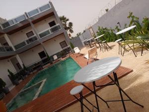 a building with a pool and a table and chairs at Résidence les Roniers de Thies in Thiès