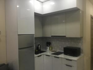 a kitchen with white cabinets and a refrigerator at Twin in Batumi