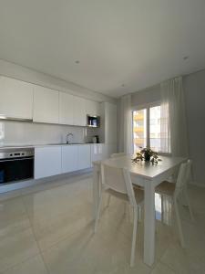 una cucina bianca con tavolo e sedie bianchi di Iate Residence a Portimão