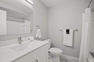a white bathroom with a toilet and a sink at Peaceful & Trendy Unit Near Attractions in Rochester Hills +5 photos