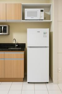 a white refrigerator in a kitchen with a microwave at Ponta Negra Flats Partic in Natal