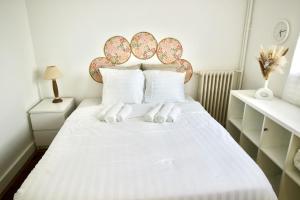 a bedroom with a white bed with white pillows at Nid Asnières escapade cosy aux portes de Paris in Asnières-sur-Seine