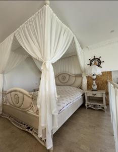 una camera da letto con letto a baldacchino con tende bianche di Маленький рай у моря a Odessa Altre 7 foto