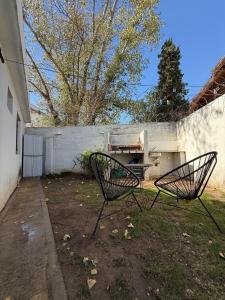 two chairs sitting in a yard next to a wall at Depto Allende in Cordoba
