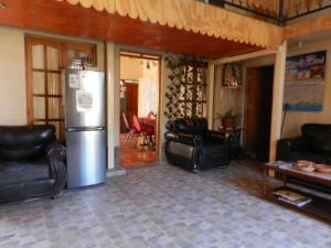 sala de estar con sillas de cuero y nevera en Hostal Illari, en San Pedro de Atacama