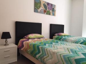 a bedroom with two beds and a dresser with a lamp at Paraíso à Beira-Mar - Sol&Praia in Portimão