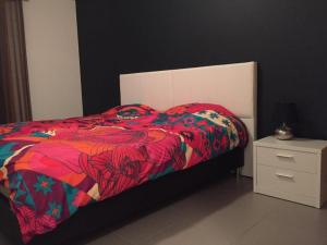 a bed with a colorful blanket and a night stand at Paraíso à Beira-Mar - Sol&Praia in Portimão