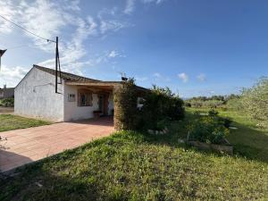 un pequeño edificio blanco en un campo con patio en Masia en el Delta del Ebro, en L'Aldea