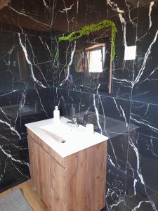 a bathroom with a sink and a black marble wall at Encanto da Aldeia in Torre de Moncorvo +26 photos