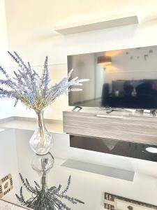 a vase with flowers on a table in front of a tv at Imperial Villas I Casa Yei in Puerto del Carmen