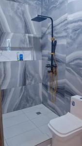 a bathroom with a shower and a toilet at Aloha Suites Odza - by Skyline Residence Services in Yaoundé