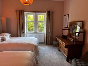 a bedroom with two beds and a television and a window at Clashmore House Garden Cottage Dornoch in Dornoch
