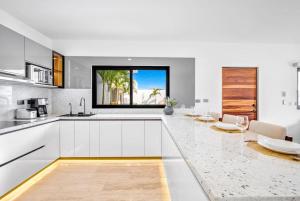 a kitchen with white cabinets and a large window at Lugar tranquilo y elegante in Cabo San Lucas