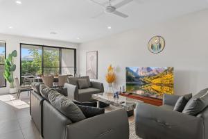 una sala de estar con sofás y una pintura en la pared en Luxury 4BR Home with Pool Gym and BBQ in Helensvale, en Gold Coast