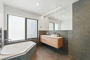a bathroom with a tub and a sink and a mirror at Modern Coastal Retreat and Hot Tub in Carlton +36 photos