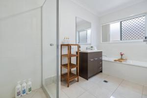 a bathroom with a shower and a sink and a tub at Modern 3BR Home in Peaceful Deebing Heights in Loamside +26 photos