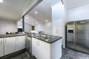 a kitchen with white cabinets and a stainless steel refrigerator at Spacious 5BR Retreat with Balcony Near Hotspots in Springwood