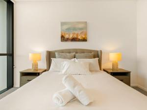 a bedroom with a large white bed with two lamps at 2BR West End Apt with Parking Walk to Convention Ctr in Brisbane