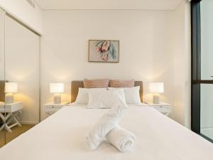 a white bed with a pile of towels on it at 2BR West End Apt with Parking Walk to Convention Ctr in Brisbane