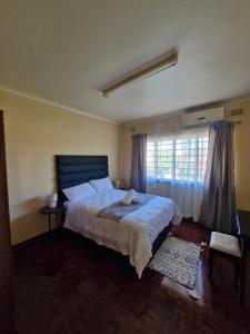a bedroom with a large bed and a window at Tettey Happy Home in Durban +9 photos