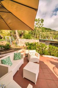 Eine Terrasse mit Sofas und Stühlen unter einem großen Sonnenschirm in der Unterkunft Villa Lorelei in Massa Lubrense