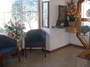 a waiting room with two chairs and a mirror and flowers at Mt Kuring-Gai Motel in Mount Kuring-Gai