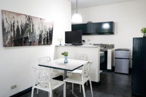a kitchen with a table and white chairs in a room at Natos Residences - Los Angeles in Bacolod