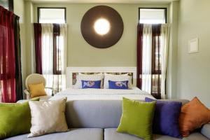 um quarto com uma cama e um sofá com almofadas coloridas em Amphawa Caza Platuu em Amphawa