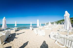 a sandy beach with white chairs and umbrellas at Beachfront, 2 Bed with Sea Views in Elenite