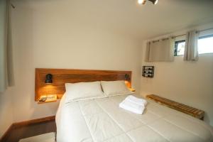 a bedroom with a large white bed with a wooden headboard at Suíte jasmim rosa in Campos do Jordão
