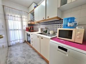 a small kitchen with a sink and a microwave at Duplex Victoria in Los Alcázares