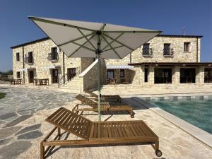 a group of benches with an umbrella next to a pool at Hotel & Villas - TERIZIS Le Rocher in Bŭlgarevo