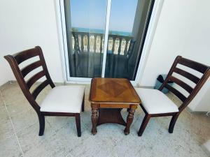 two chairs and a table in front of a window at Sea View Studio 4 Royal Breeze Breezeسي ويو ستوديو رويال بريز in Ras al Khaimah