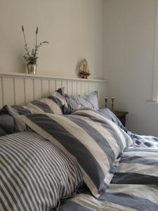 a bed with striped pillows on it in a room at Badepensionat Sandloppen in Sandvig