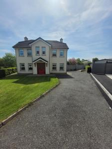 a white house with a red door on a driveway at Connollys Holiday Home Doohamlet Castleblayney in Monaghan