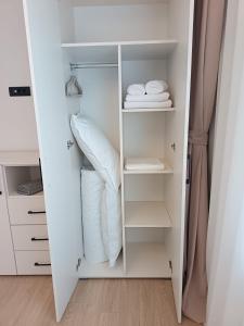 ポイアナ・ブラショフにあるCozy Retreat Grand Chalet Aparthotelのクローゼット(白い棚、折りたたみ式タオル付)