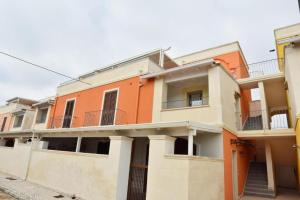 un edificio de apartamentos de color naranja y blanco en OWNER ITALY Residence, en Torre Lapillo