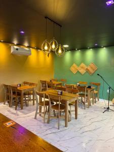 a dining room with tables and chairs and a green wall at Hotel Calleb in Presidente Figueiredo