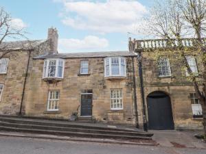 an old stone house with a black door at Westhill House in Warkworth