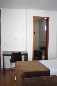a bedroom with two beds and a desk and a chair at Letto Business Antigo Hotel Ornatus Proximo a Santa Casa in Porto Alegre