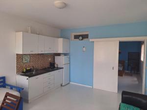 una cucina con armadi bianchi e parete blu di Útulný apartmán na Praia de Chaves, Boa Vista a Sal Rei Altre 13 foto