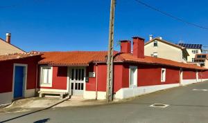 a red and white building on the side of a street at Casa rural entre Santiago Compostela y La Coruña in Ordes