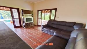 a living room with a couch and a television at Chacara em Cássia com Piscina e Lago in CÃ¡ssia