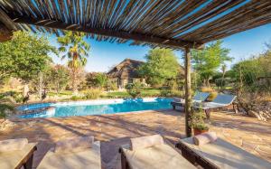 an outdoor patio with a swimming pool and a pergola at Immanuel Wilderness Lodge in Windhoek